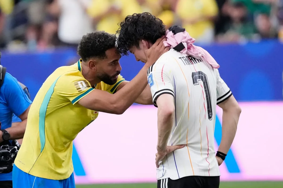Woman comforts Japan fan with Brazilian flag after World Cup Round of 32 clash