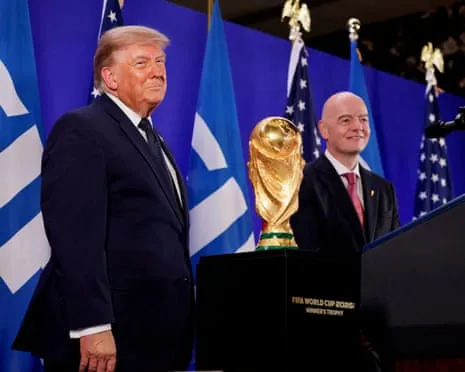 Donald Trump and FIFA President Gianni Infantino stand on either side of the World Cup trophy with flags behind them
