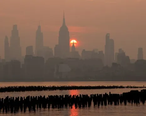 New York City skyline silhouetted in haze from Canadian wildfire smoke with a faint sun visible